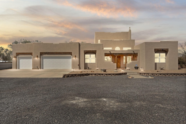 pueblo-style home featuring concrete driveway, stucco siding, and a garage