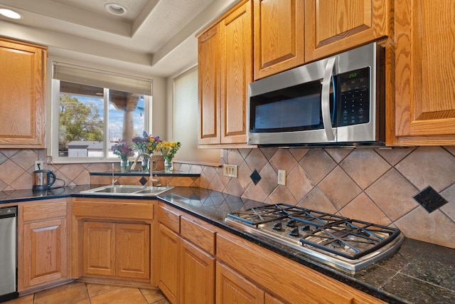 kitchen with recessed lighting, a sink, stainless steel appliances, a raised ceiling, and backsplash