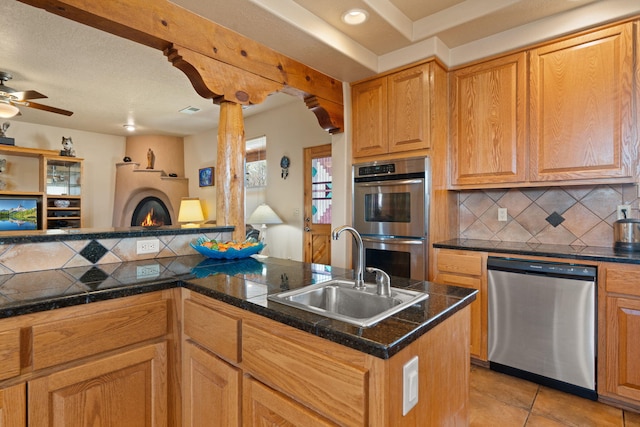 kitchen with tasteful backsplash, appliances with stainless steel finishes, light tile patterned floors, and a sink