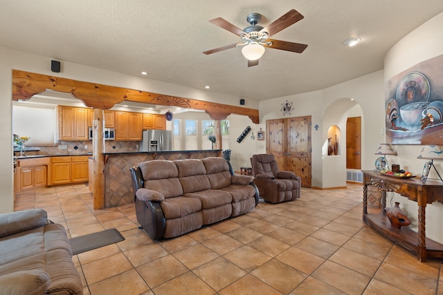 living area featuring visible vents, light tile patterned floors, arched walkways, ceiling fan, and recessed lighting
