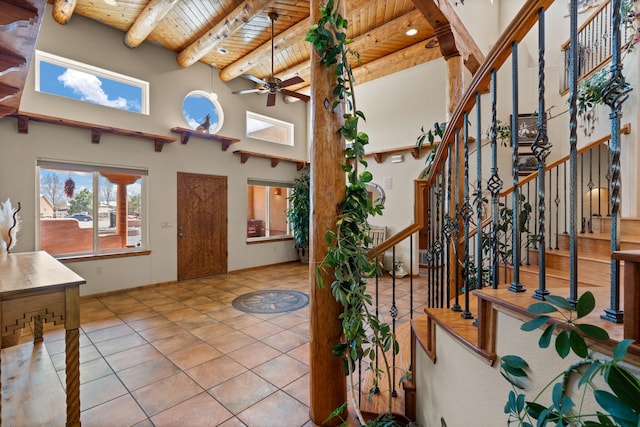 entryway with tile patterned flooring, stairs, beam ceiling, ceiling fan, and wood ceiling
