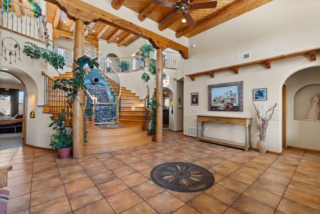 interior space featuring arched walkways, a high ceiling, beam ceiling, and ceiling fan