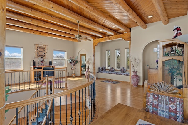 hallway with an upstairs landing, beam ceiling, arched walkways, wood ceiling, and wood finished floors