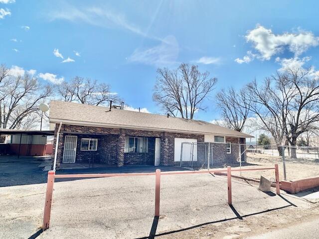 ranch-style home featuring a carport and fence