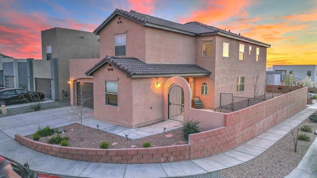 8717 Sevano Cir NE, Albuquerque, NM 87113 - mediterranean / spanish-style home featuring a tile roof, an attached garage, stucco siding, driveway, and a fenced front yard