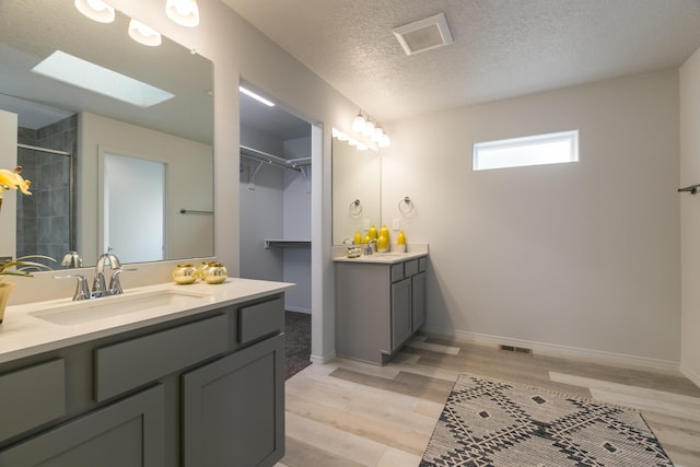 9620 Sage Ranch Ct SW, Albuquerque, NM 87121 - full bath featuring wood finished floors, vanity, a skylight, tiled shower, and a textured ceiling