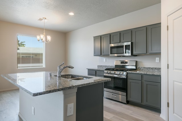 9600 Sage Ranch Ct SW, Albuquerque, NM 87121 - kitchen featuring stainless steel appliances, light wood-style floors, gray cabinetry, a textured ceiling, and stone countertops