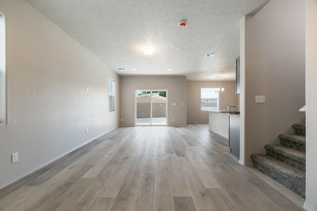 9600 Sage Ranch Ct SW, Albuquerque, NM 87121 - unfurnished living room featuring light wood finished floors, a textured ceiling, and stairs
