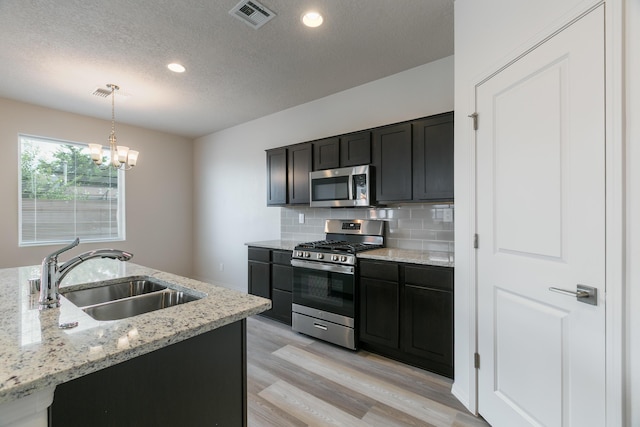9504 Sage Ranch Ct SW, Albuquerque, NM 87121 - kitchen featuring stainless steel appliances, light wood-style flooring, a textured ceiling, pendant lighting, and decorative backsplash