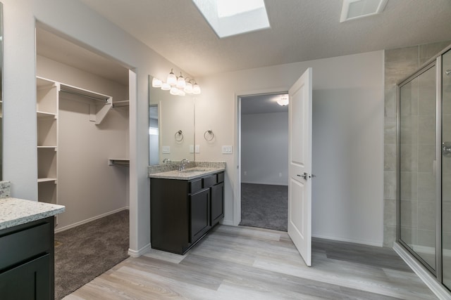 9504 Sage Ranch Ct SW, Albuquerque, NM 87121 - full bathroom with vanity, wood finished floors, a shower stall, a spacious closet, and a skylight