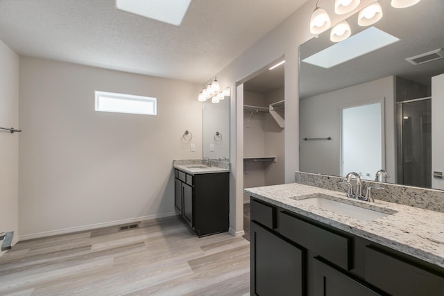 9504 Sage Ranch Ct SW, Albuquerque, NM 87121 - bathroom with a stall shower, two vanities, wood finished floors, a skylight, and a walk in closet