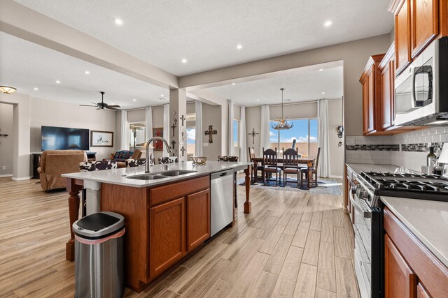 460 Rio Chama Cir SW, Los Lunas, NM 87031 - kitchen featuring stainless steel appliances, a sink, open floor plan, brown cabinetry, and recessed lighting