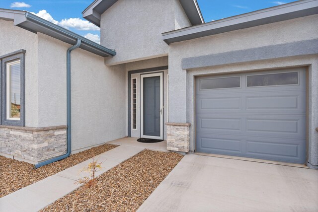 460 Rio Chama Cir SW, Los Lunas, NM 87031 - view of exterior entry featuring stone siding, stucco siding, a garage, and concrete driveway