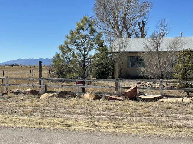 view of yard with a rural view, fence, and a mountain view