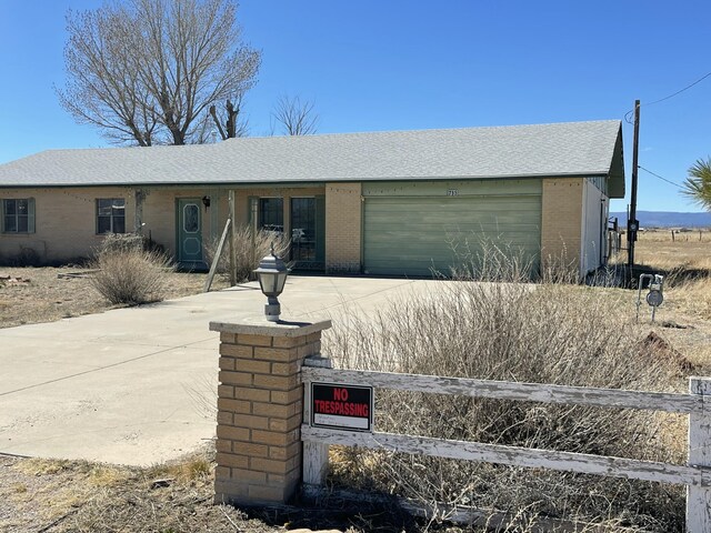 ranch-style home with driveway, an attached garage, and brick siding