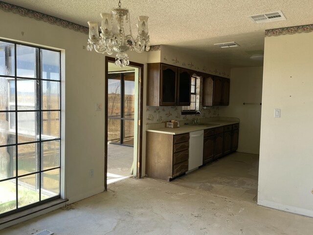 kitchen with light countertops, visible vents, a chandelier, dishwasher, and a sink