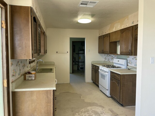 kitchen with light countertops, a sink, white gas stove, and visible vents