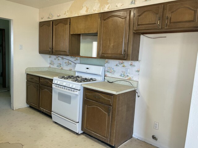 kitchen with light countertops, white range with gas cooktop, dark brown cabinetry, and light floors