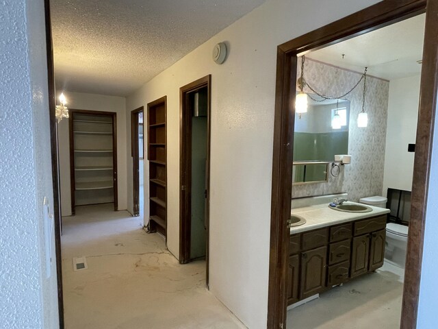 hall with concrete flooring, a textured ceiling, and a sink