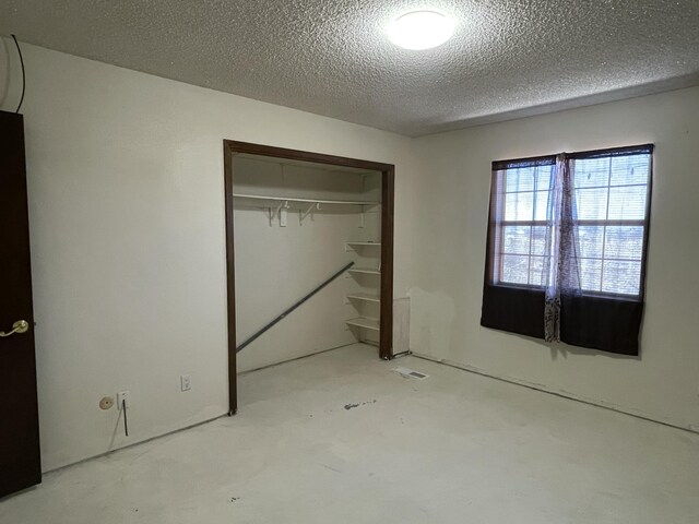unfurnished bedroom featuring a closet, concrete floors, and a textured ceiling