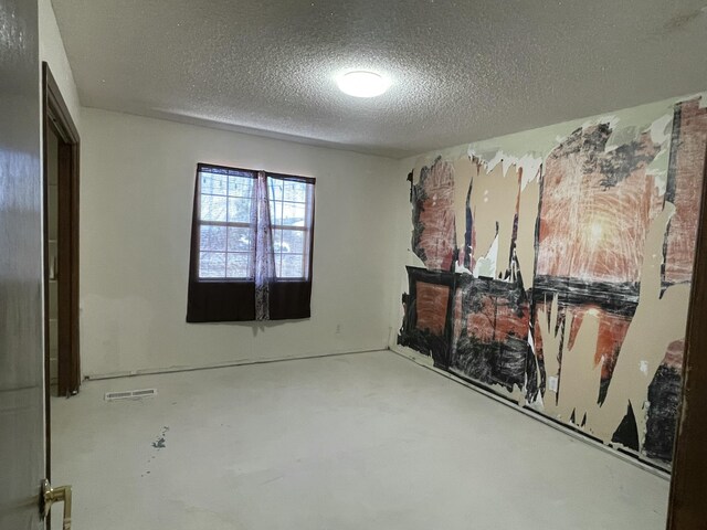 unfurnished room with concrete flooring, a textured ceiling, and visible vents