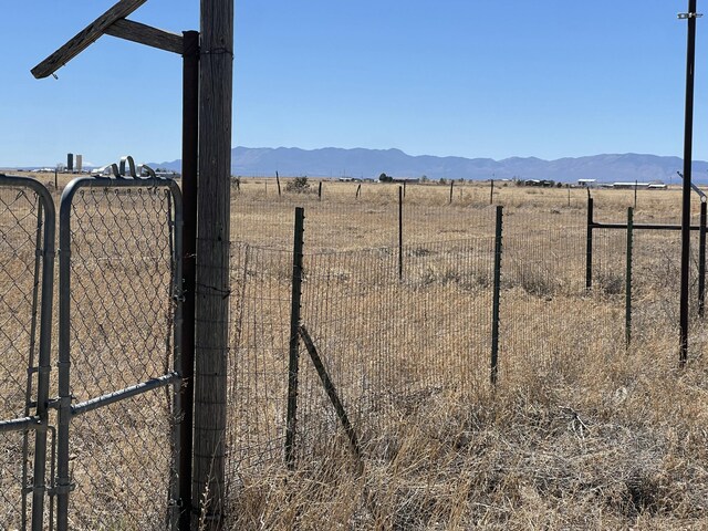 view of yard with a gate, a mountain view, fence, and a rural view
