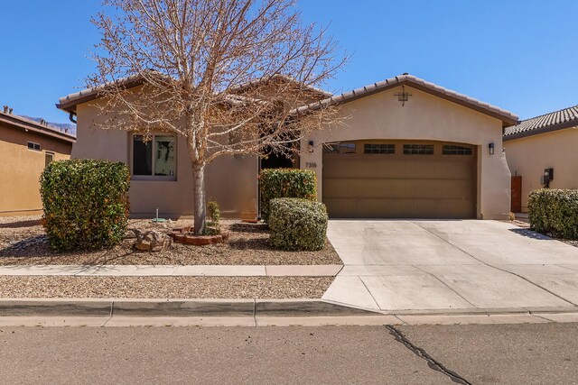 view of front of house with a garage, stucco siding, concrete driveway, and a tiled roof