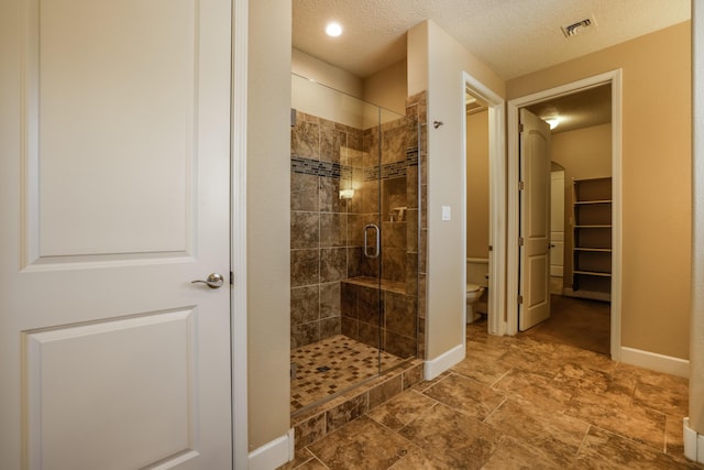 full bath featuring toilet, a stall shower, visible vents, and baseboards