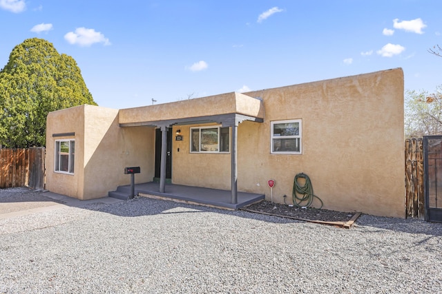 adobe home with stucco siding and fence