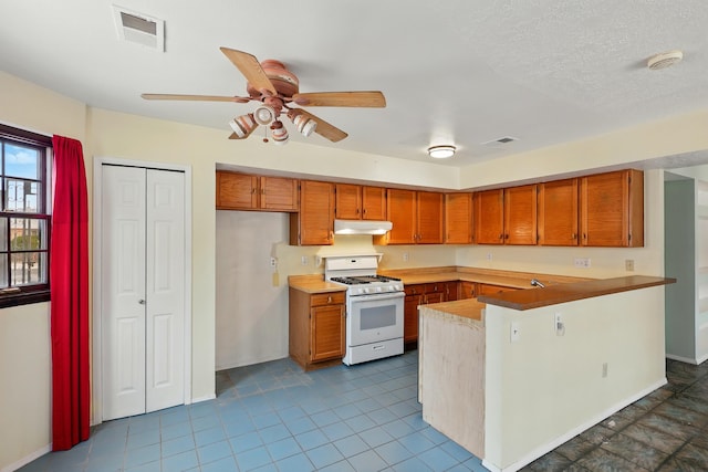 404 Pyrite Dr NE, Rio Rancho, NM 87124 - kitchen with white range with gas stovetop, under cabinet range hood, brown cabinetry, and a peninsula