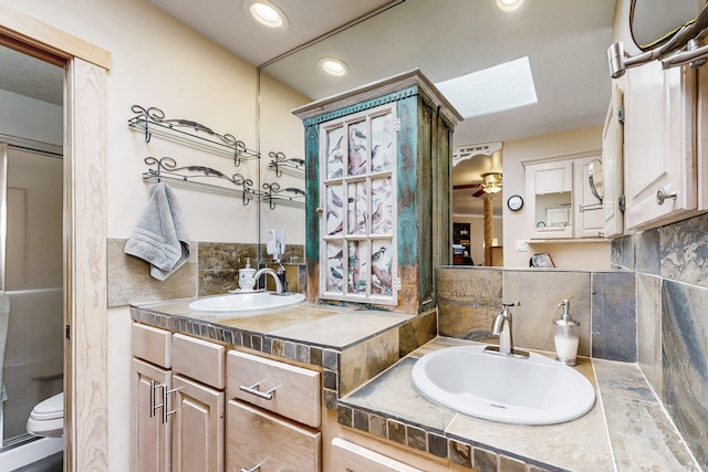 2544 Sandia Loop NE, Rio Rancho, NM 87144 - full bathroom featuring decorative backsplash, a skylight, vanity, toilet, and recessed lighting
