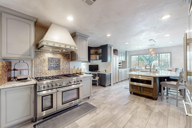 kitchen featuring tasteful backsplash, open shelves, gray cabinets, stainless steel appliances, and custom range hood
