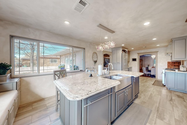 kitchen with visible vents, a sink, arched walkways, gray cabinetry, and stainless steel stove
