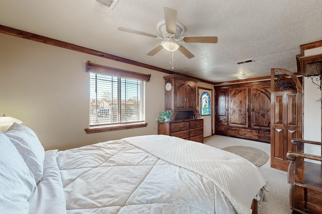 bedroom with a textured ceiling, visible vents, light colored carpet, ceiling fan, and crown molding