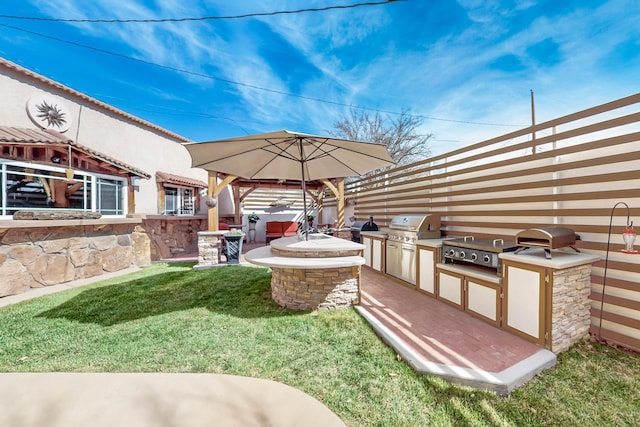 view of yard featuring a jacuzzi, exterior kitchen, fence, a patio area, and a gazebo