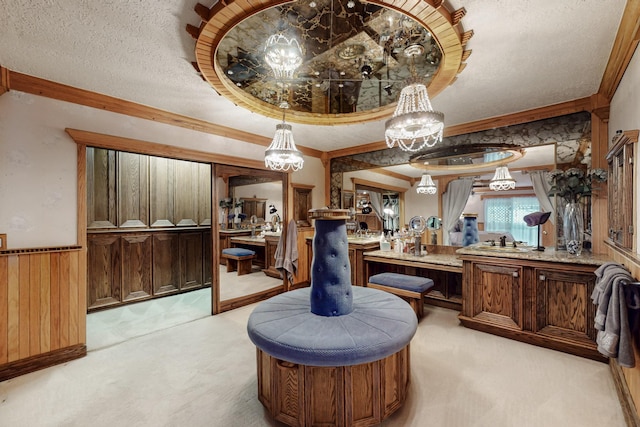 bathroom featuring a wainscoted wall, a textured ceiling, wood walls, crown molding, and vanity