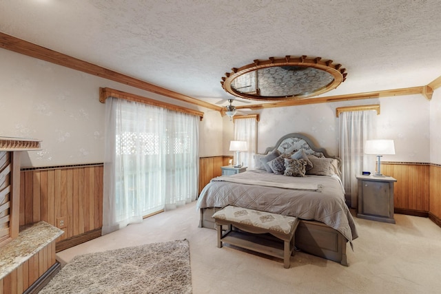 bedroom featuring wood walls, a wainscoted wall, a textured ceiling, and light carpet