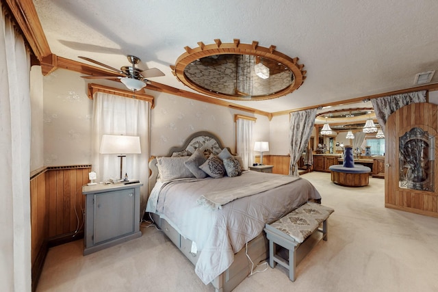 bedroom featuring wainscoting, visible vents, a textured ceiling, and light colored carpet