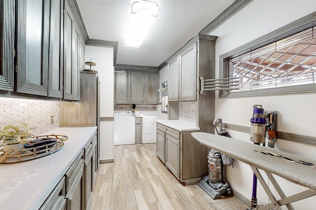 kitchen with washing machine and dryer, decorative backsplash, light countertops, and light wood-style floors
