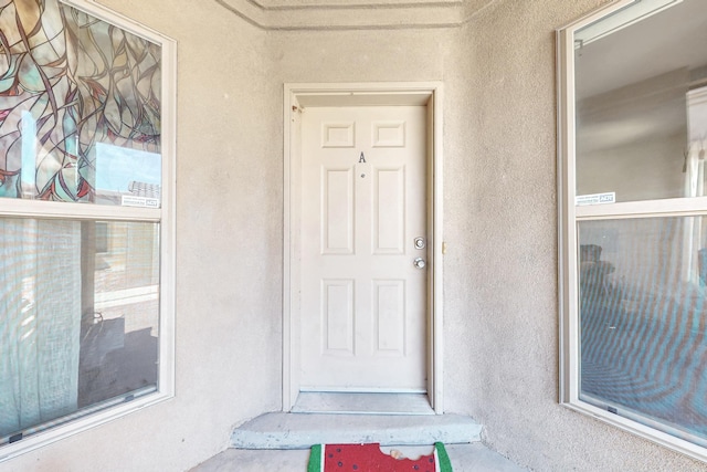 doorway to property featuring stucco siding