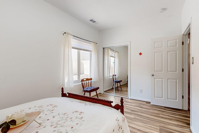 bedroom featuring a closet, baseboards, visible vents, and light wood-style floors