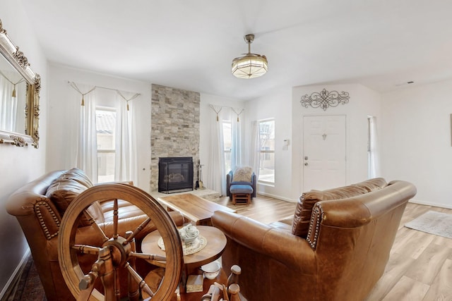 living room with a healthy amount of sunlight, baseboards, light wood-style floors, and a fireplace