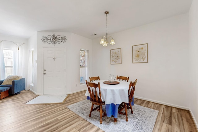 dining area featuring baseboards, wood finished floors, and a notable chandelier