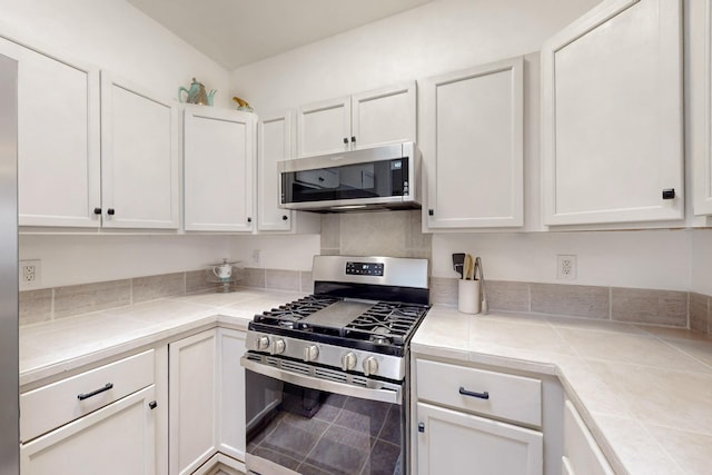 kitchen featuring white cabinets, stainless steel appliances, and tile countertops