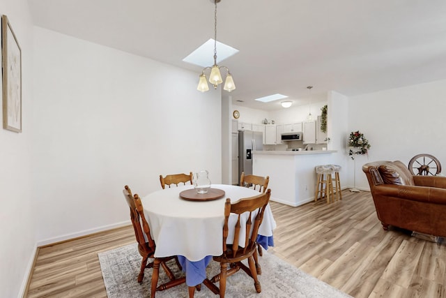 dining room with light wood finished floors, baseboards, and a skylight