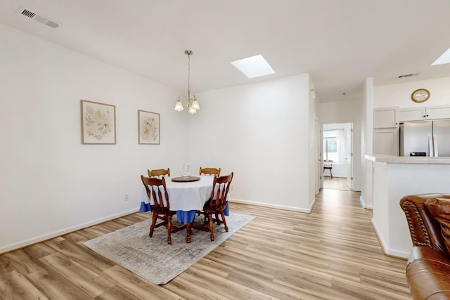 dining room with visible vents, a skylight, light wood-type flooring, and an inviting chandelier