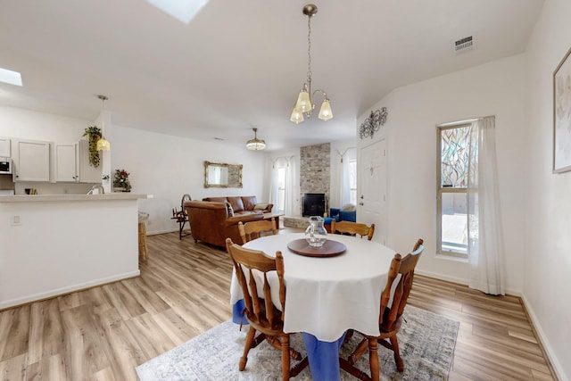 dining area with baseboards, visible vents, a chandelier, and light wood finished floors