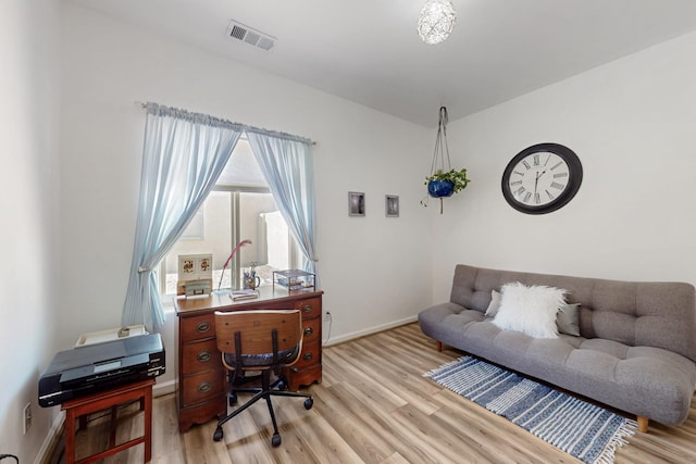 office space with baseboards, light wood-style floors, and visible vents