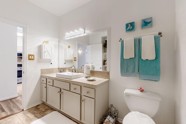 bathroom with baseboards, toilet, and vanity