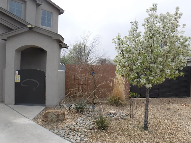 view of side of home featuring fence and stucco siding